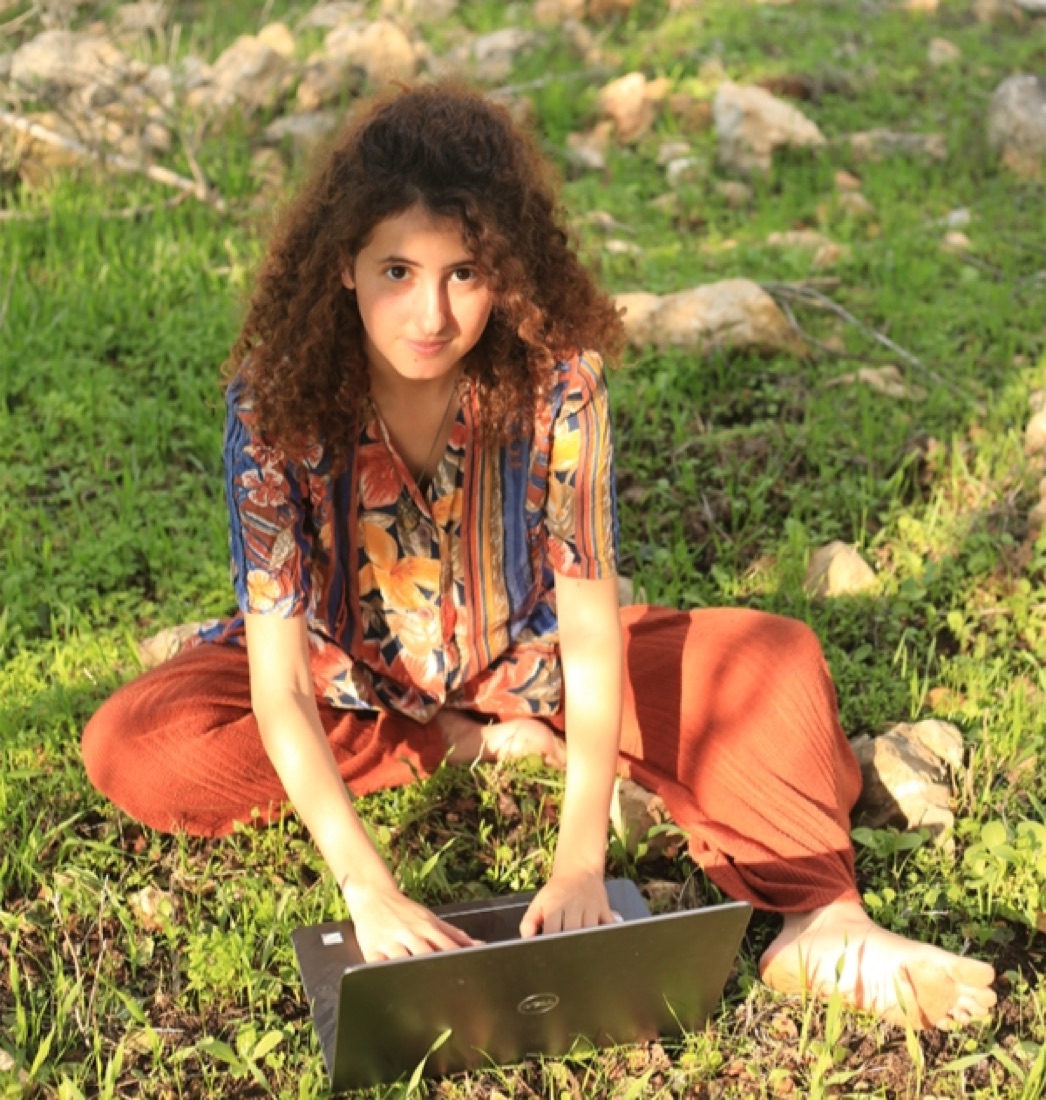 קארין יושבת על הדשא עם מחשב נייד